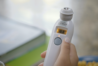 A hand holding the Exergen TAT-2000C Temporal Artery Thermometer